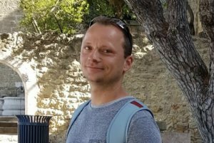 Christian Wirth lächelnd vor historischen Steingebäuden im Freien
