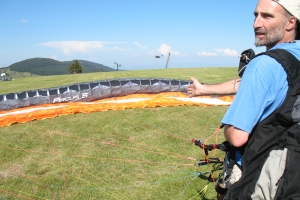 Hari Huber am Startplatz mit aufgespanntem Gleitschirm, Berge und blauer Himmel im Hintergrund