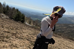 Kerstin Kaiser mit Sonnenhut auf einem Berggipfel, weite Tallandschaft im Hintergrund
