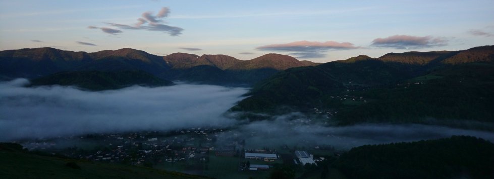 Das Thurtal in der Dämmerung: eine Nebelbank über den Dörfern im Talgrund, bewaldete Vogesenkämme im letzten Licht